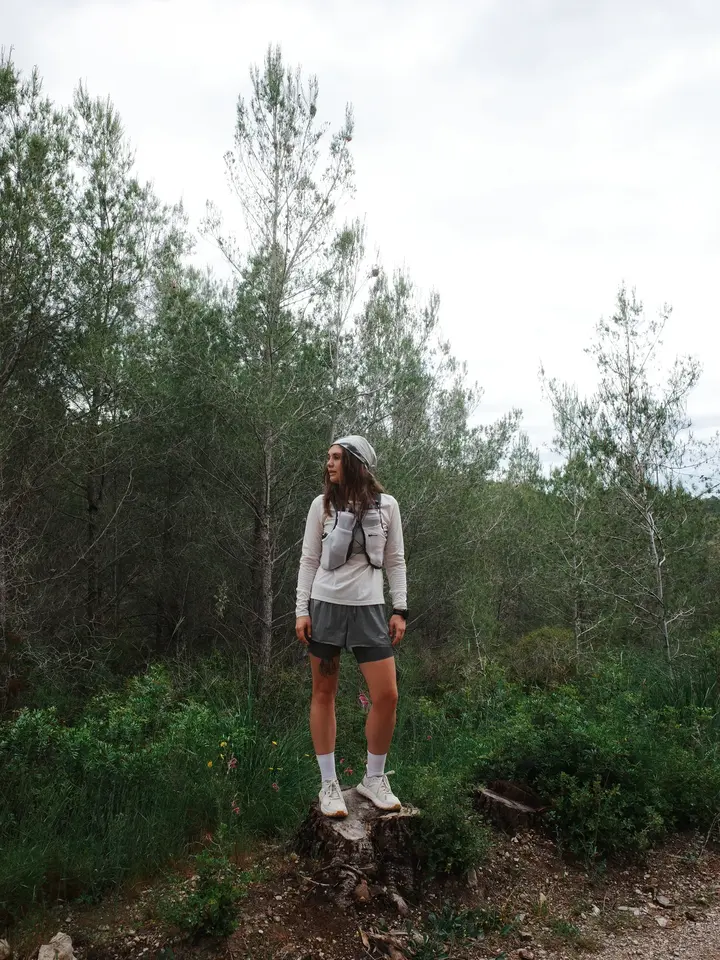 A person standing on a tree stump among green trees