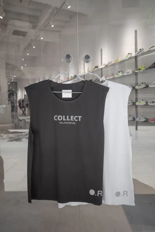 Two sleeveless shirts, one black and one white, hanging in a shop