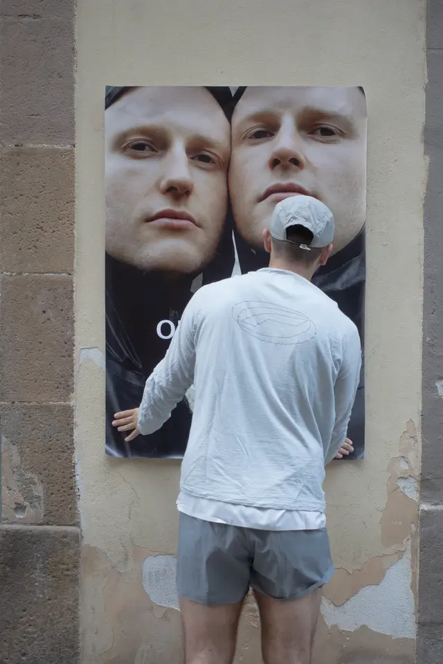 A person standing in front of a poster of two faces