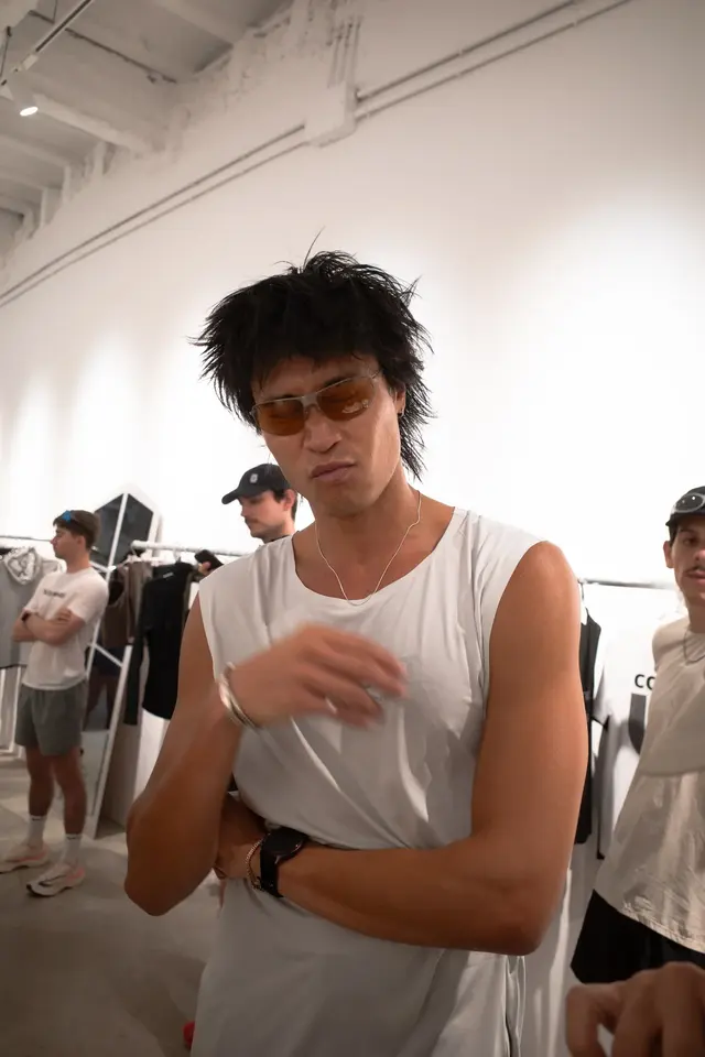 A person in a white tank top standing on a busy street