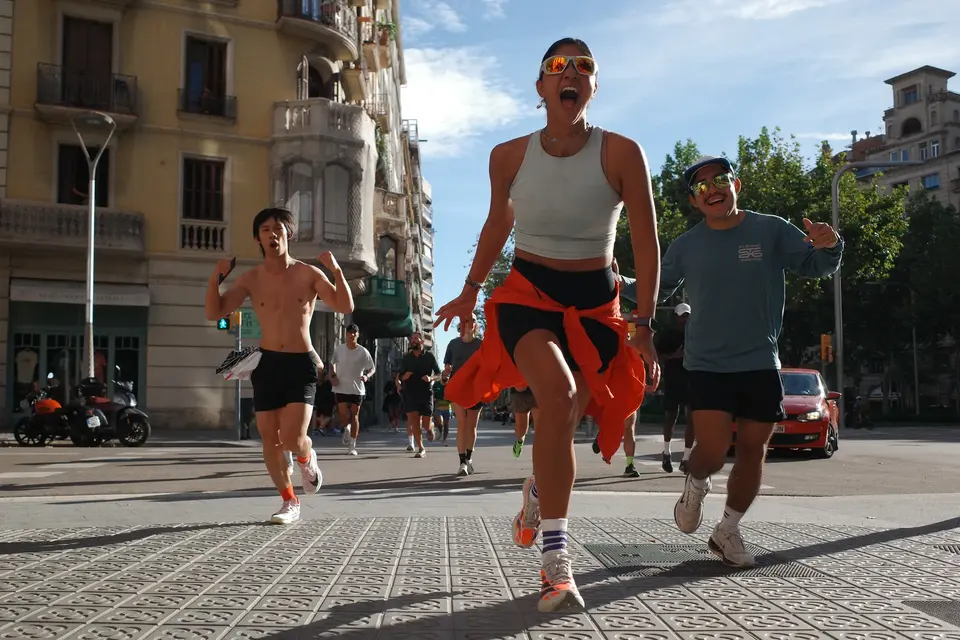 Runners on a city street, one carrying a small flag