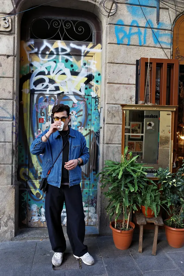 A person in a denim jacket standing in a graffiti-covered doorway