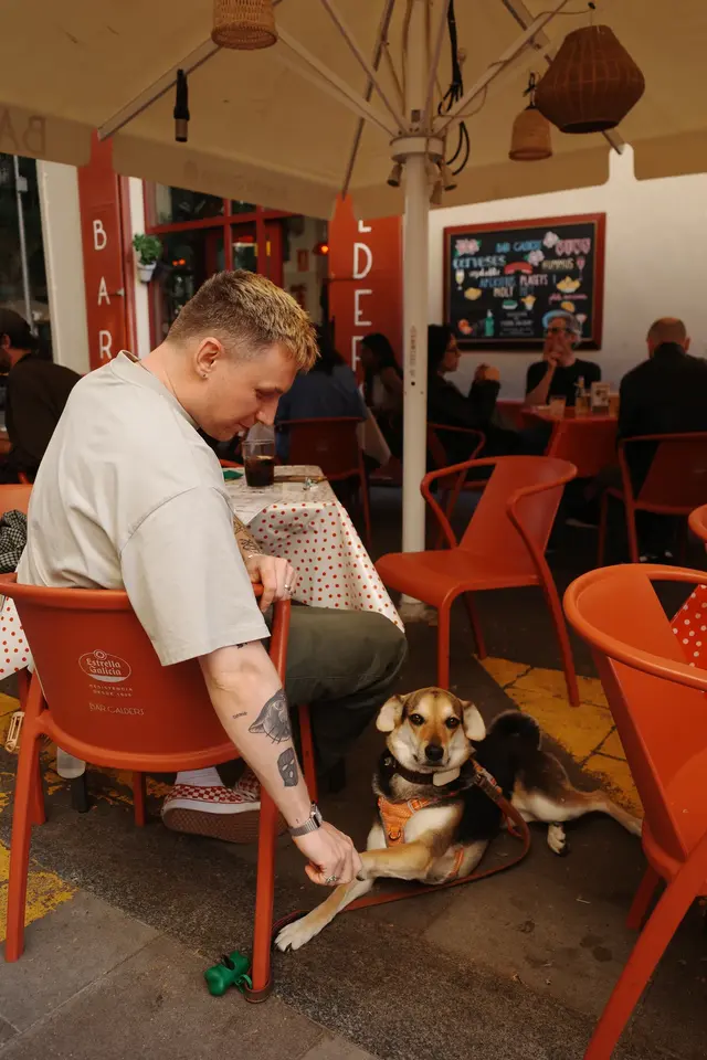 A person seated with a dog in a room of orange chairs