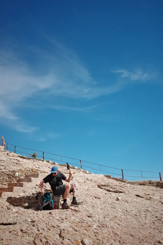 A person climbing a rock face against a blue sky